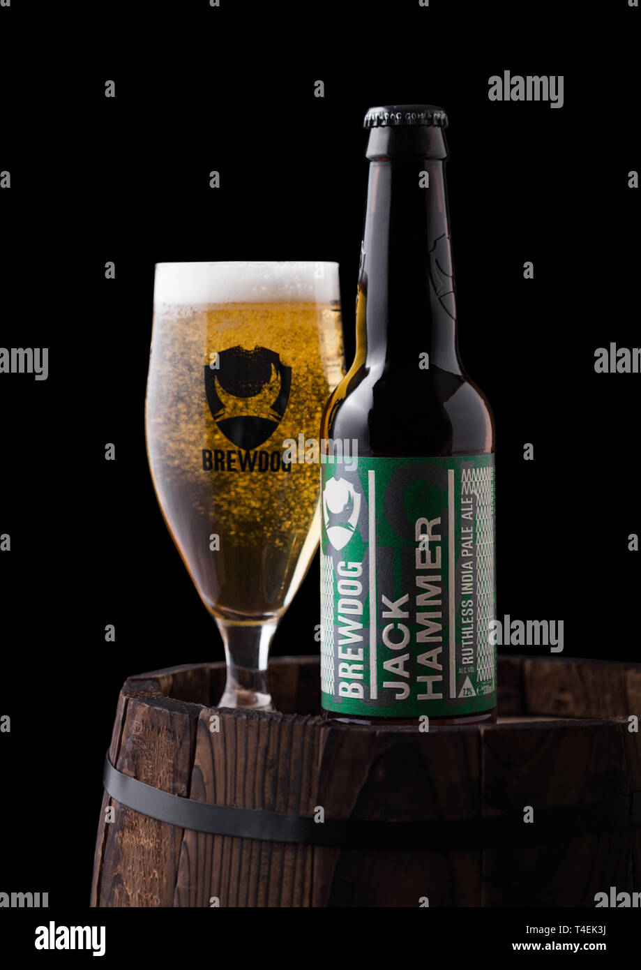 LONDON, UK - JUNE 06, 2018: Bottle and glass of Jack Hammer indian pale ale beer, from the Brewdog brewery on old wooden barrel on black background. Stock Photo