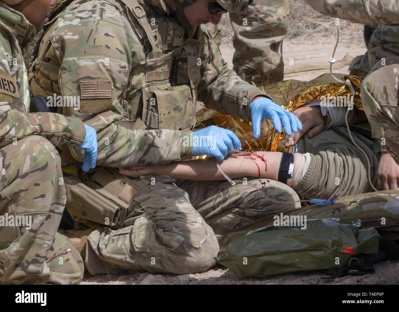 Airmen from the 823d Base Defense Squadron practice tactical combat casualty care as part of the Mission Readiness Exercise (MRX) scenario at Camp Guernsey, Wyo., March 26, 2019. Under the supervision of a medic, the Airmen inserted an IV into the simulated victim’s arm. The MRX scenario put small, isolated teams of defenders in multiple stressful scenarios to practice decision making in an adaptive basing situation. Stock Photo