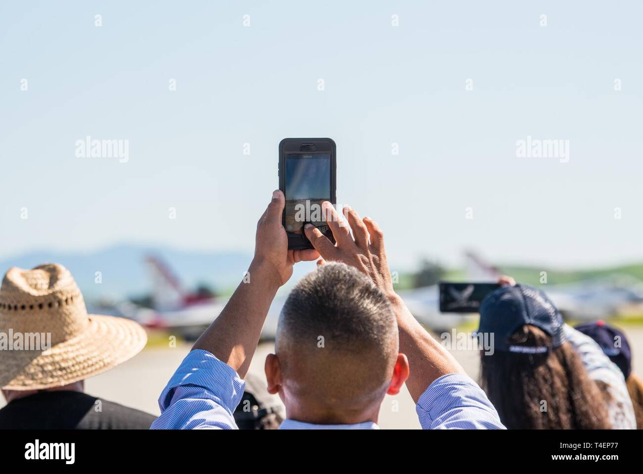 A spectator takes a video during the U.S. Air Force Thunderbirds demonstration teams performance during the “Thunder over the Bay” Air Show at Travis Air Force Base, California, March 31, 2019. In addition to the U.S. Air Force Thunderbirds aerial demonstration team, the two-day event featured performances by the U.S. Army Golden Knights parachute team, flyovers, and static displays. The event honored hometown heroes like police officers, firefighters, nurses, teachers and ordinary citizens whose selfless work made their communities safer and enhanced the quality of life. Stock Photo