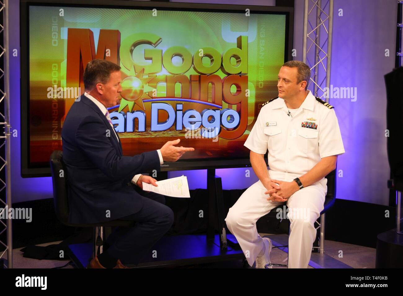 SAN DIEGO (Apr. 7, 2019) Lt. Cmdr. Rich Ray, right, an Anti-Submarine/Surface Warfare (ASW/SUW) Warfare Tactics Instructor assigned to Naval Surface and Mine Warfighting Development Center (SMWDC) sits for an interview with broadcaster Jason Austell on KUSI's Good Morning San Diego. Ray discussed his role planning the first Forward Deployed Naval Forces Surface Warfare Advanced Tactical Training (SWATT) exercise in the U.S. 7th Fleet. SWATT exercises transition Surface Force readiness into lethality by bringing warfare commanders, ships, and crews together to exercise advanced tactics at sea.  Stock Photo