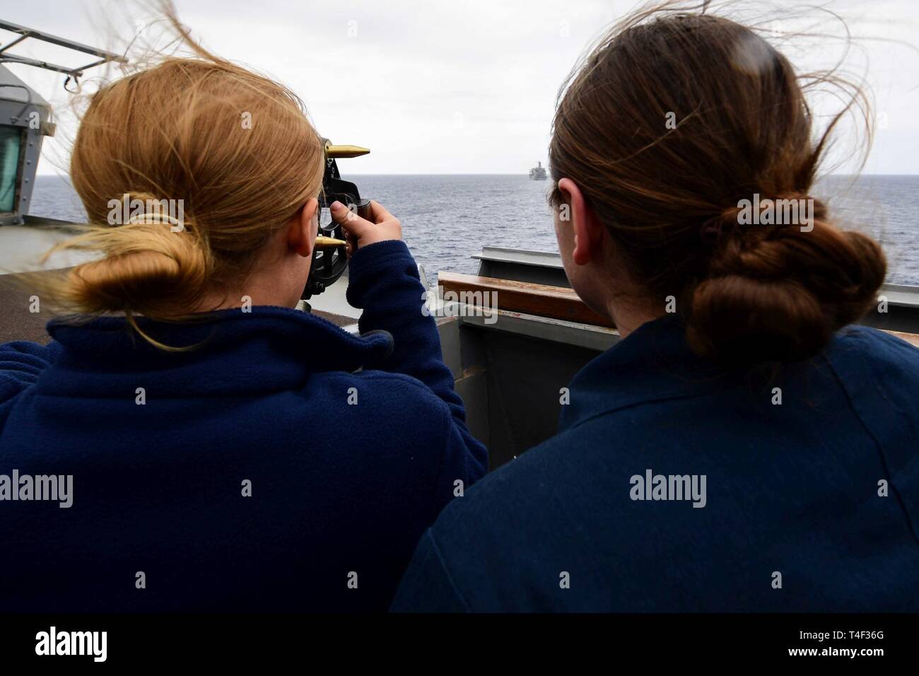 SEA (April 9, 2019) - Quartermaster 3rd Class Annie Killcrease, left, and Quartermaster 2nd Class Amy Girdler use a stadimeter to measure the distance between the Arleigh Burke-class guided-missile destroyer USS Ross (DDG 71) and the Henry J. Kaiser-class fleet replenishment oiler USNS John Lenthall (T-AO 189) before a replenishment-at-sea in the Mediterranean Sea, April 9, 2019. Ross, forward-deployed to Rota, Spain, is on its eighth patrol in the U.S. 6th Fleet area of operations in support of U.S. national security interests Europe and Africa. Stock Photo