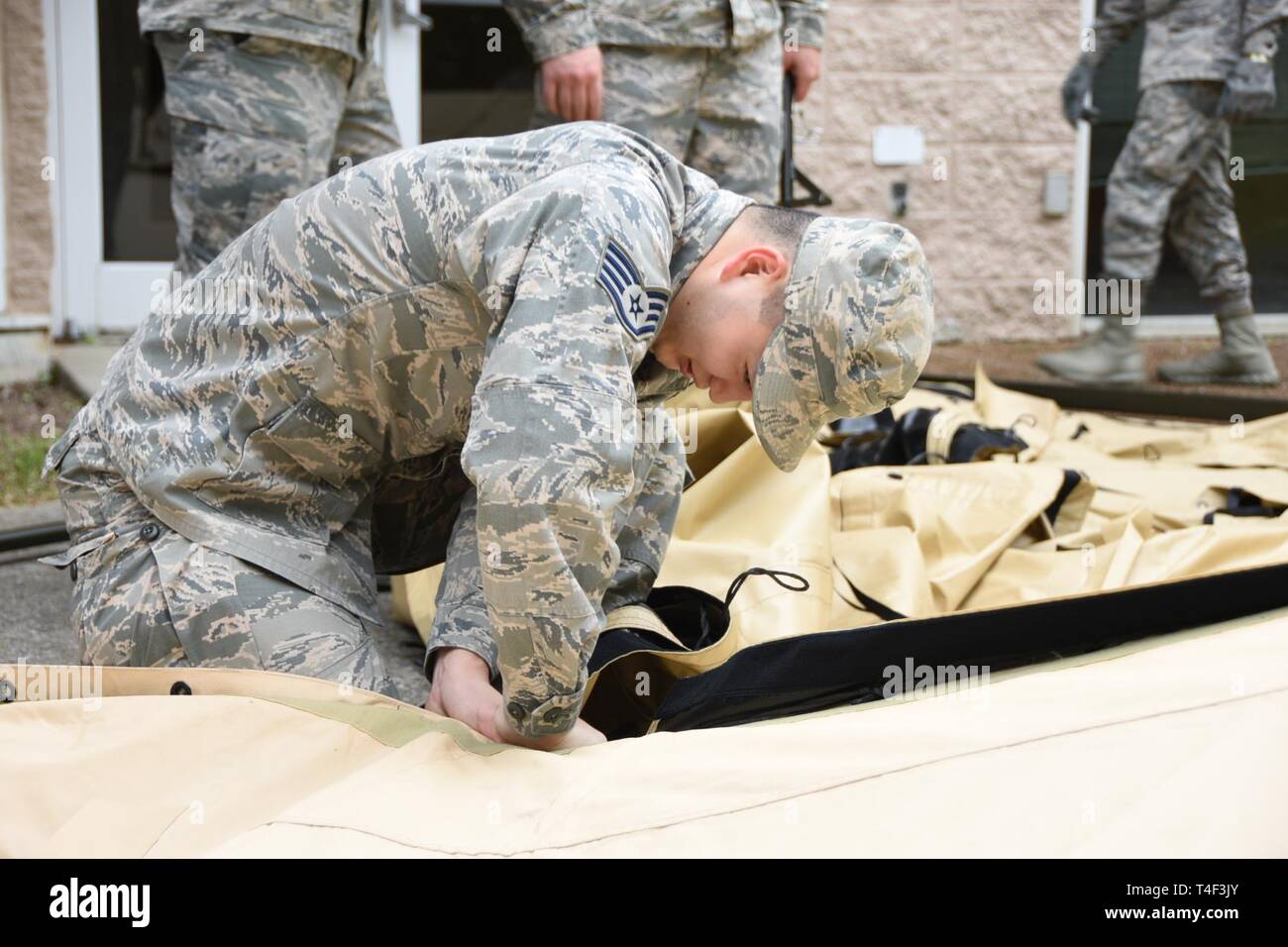 U.S. Air Force Staff Sgt. Hongwei Qin, a services journeyman with the 118th Force Support Squadron, Tennessee Air National Guard, ties down the covering of a temper tent April 4, 2019 at Berry Field Air National Guard Base, Nashville, Tennessee. Several 118th FSS members assembled the tent to set up a single pallet expeditionary kitchen. This allows services Airmen to train and be ready for potential future deployments. Stock Photo