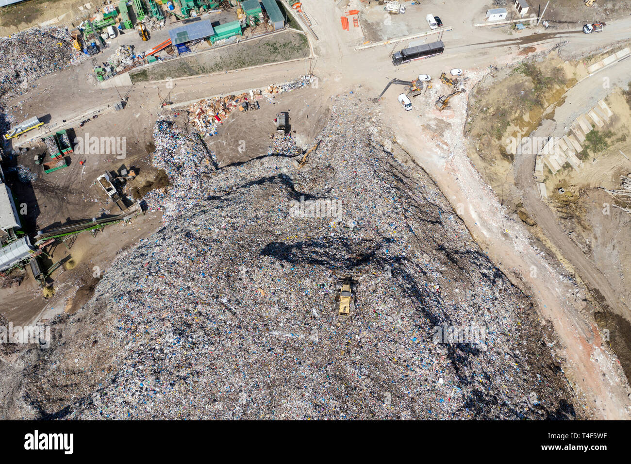 Aerial top drone view of large garbage pile, trash dump, landfill, waste from household dumping site, excavator machine is working on a mountain of ga Stock Photo