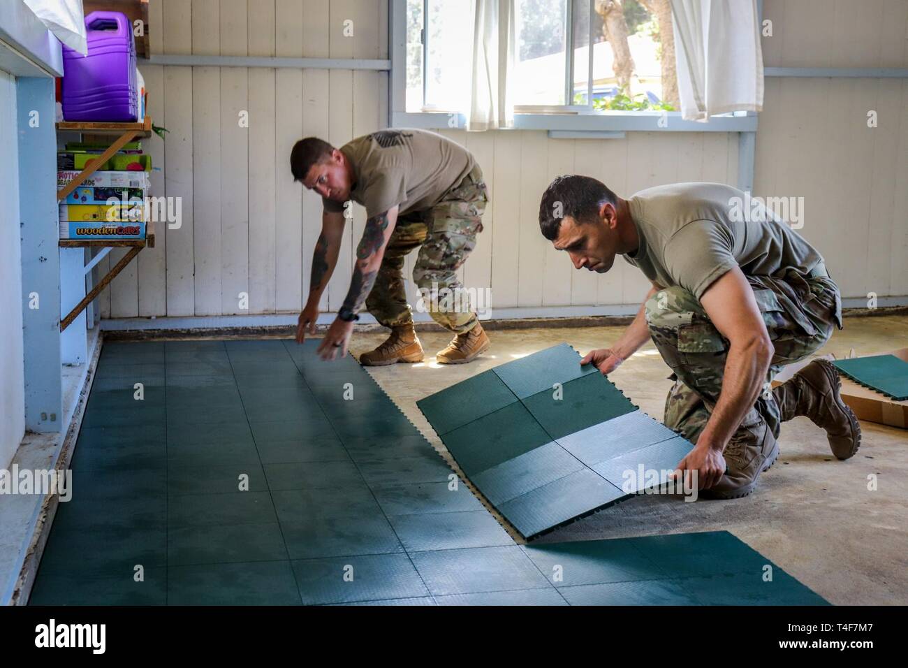 1st Sgt. Dennis Hudson (left) and Command Sgt. Major Nema Mobar (right), Soldiers assigned to 1-21 Infantry Battalion, 2nd Infantry Brigade Combat Team, 25th Infantry Division, place down plastic tiles in a building at St. James Episcopal Church, Waimea, Hawaii, April 10th, 2019. 25th ID Soldiers are conducting Exercise Lightning Strike at Pohakuloa Training Area. Soldiers come to PTA to hone their skills and improve their readiness and lethality at the premier training center of the Pacific region. Stock Photo