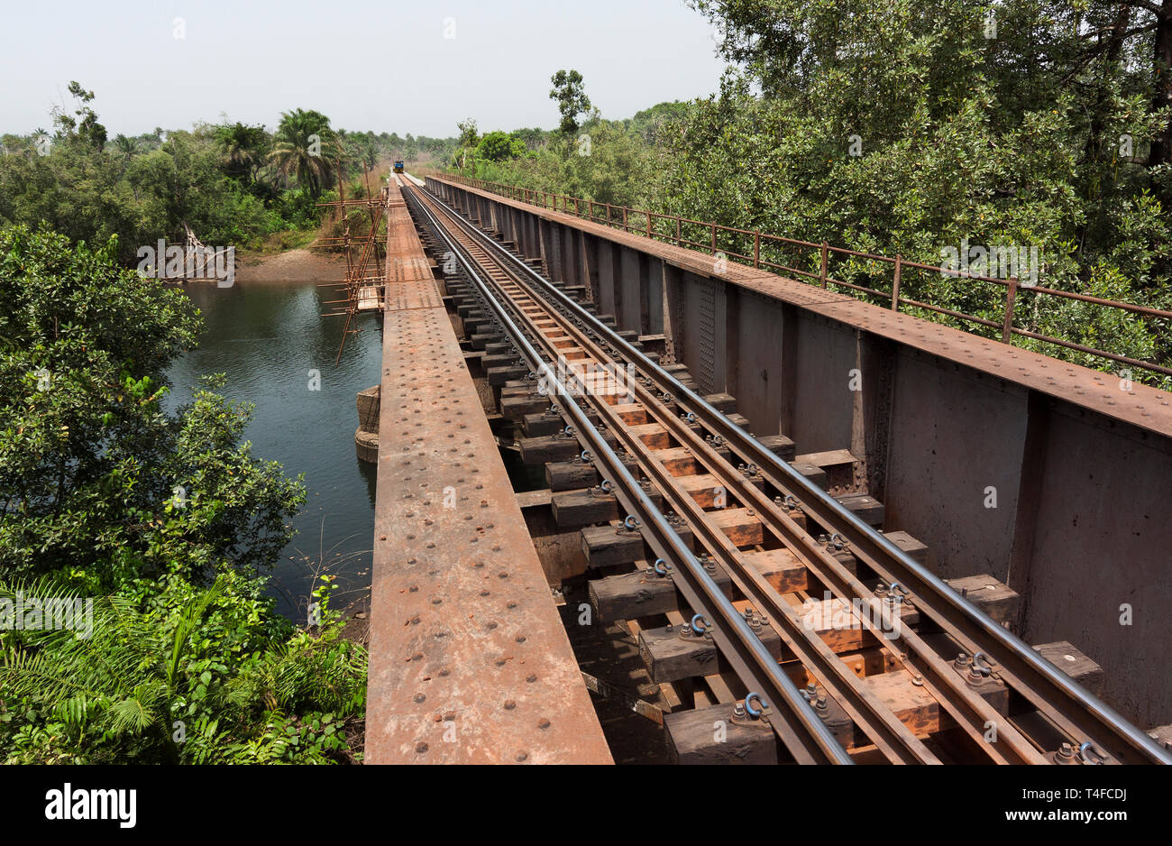 Rail and port operations for managing and transporting iron ore. Rail bridge over river near Port Loko undergoing overhaul with ore train approaching. Stock Photo
