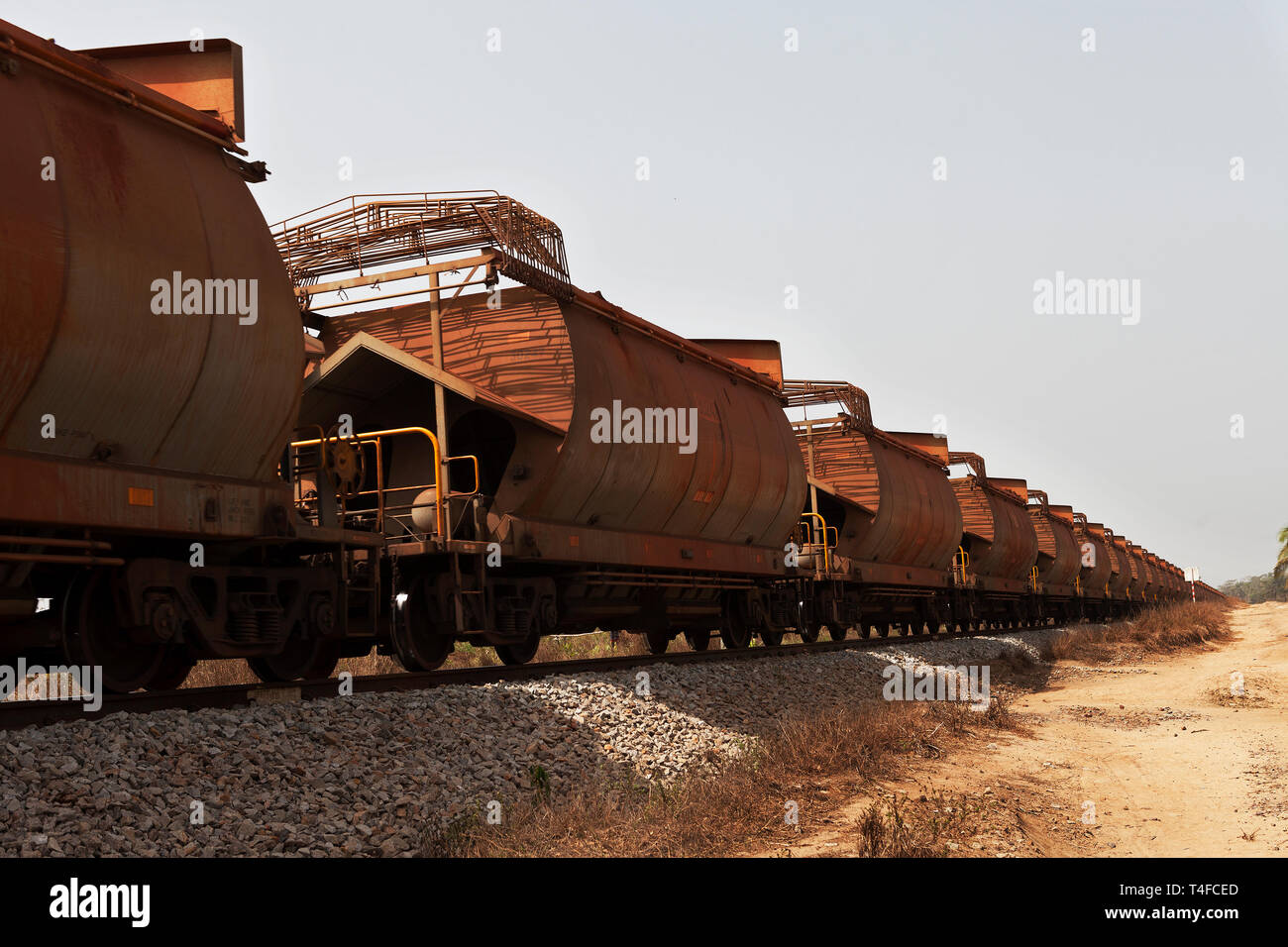 Port operations for managing and transporting iron ore. Railway wagons near port area carrying iron ore before loading onto ships for overseas markets Stock Photo