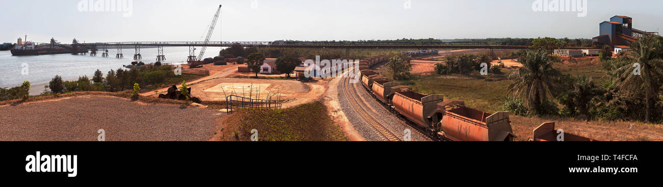 Rail & port operations for managing and transporting iron ore. Ship at loading jetty at end of conveyor belt & ore train on rail loop after discharge. Stock Photo