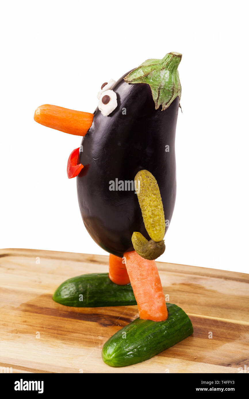 Funny figure carved out of an aubergine on a wooden board - isolated Stock Photo