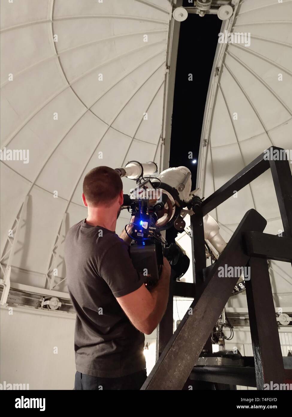 A camera operator images the Moon through the eyepiece of the U.S. Naval  Observatory's historic 12-inch refractor telescope as part of a Science  Channel documentary being filmed on the Observatory grounds. USNO