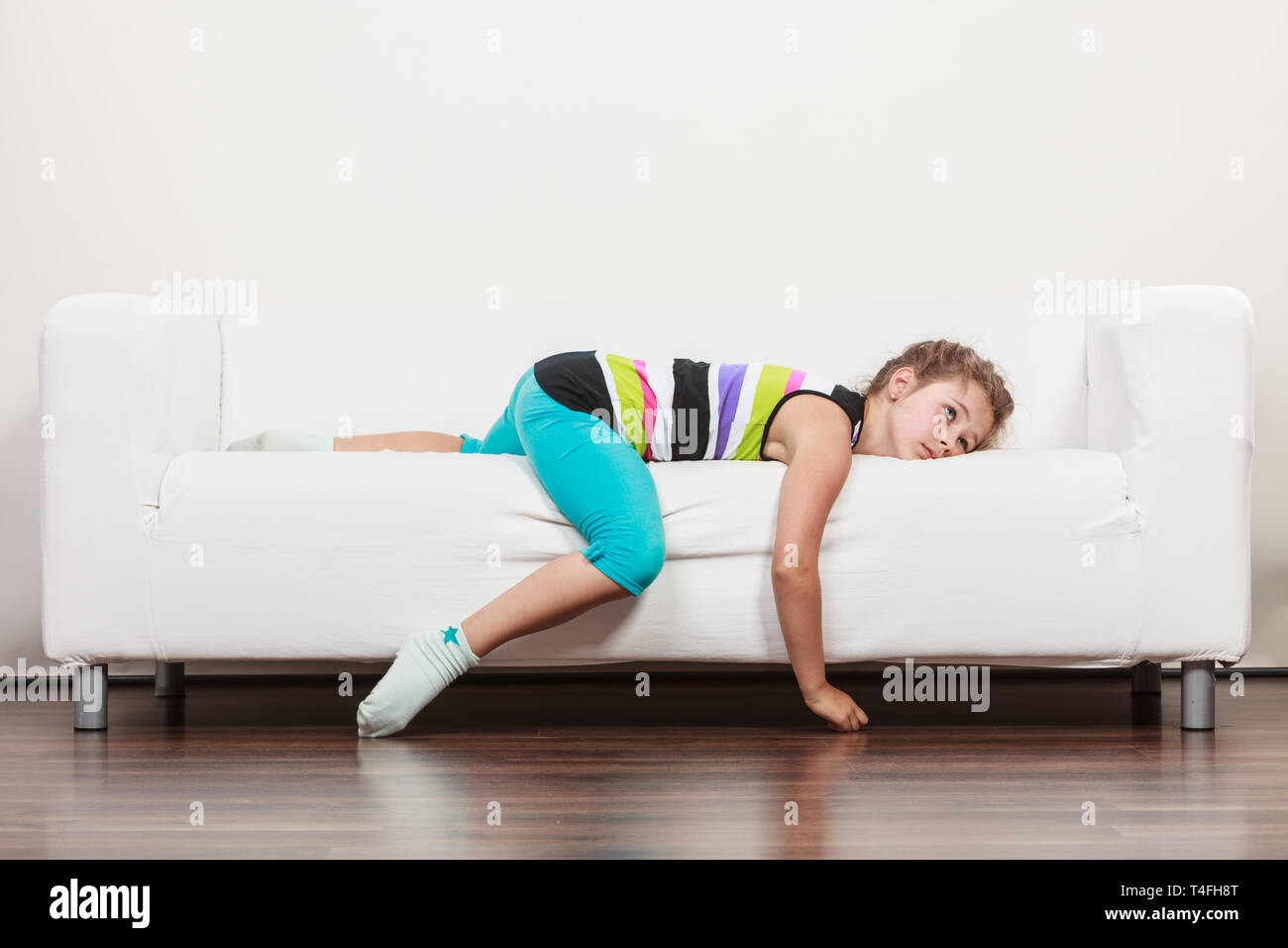 Tired exhausted lazy little girl lying on sofa at home. Sleepy kid