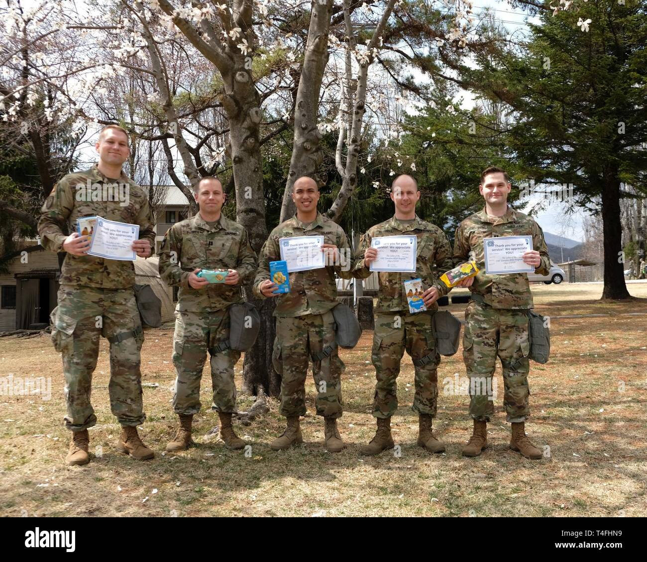 Captains with Headquarters and Headquarters Battery, 210th Field Artillery Brigade, 2nd Infantry Division/ROK-U.S. Combined Division, pose for a photo holding cookies sent to them by students from the University of North Carolina's Executive Masters of Business Administration class of 2019, April 11, 2019, Camp Casey, Republic of Korea. Several students voluntarily sent Girl Scout cookies to one of the officers to share. Three of the five officers voted caramel delights as their favorite cookie. Stock Photo