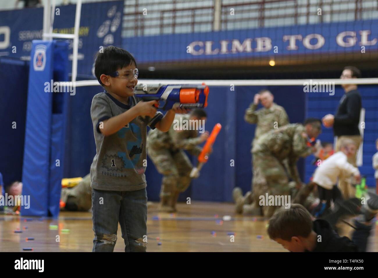 Miniature warriors from Families across 2nd Brigade Combat Team, 10th Mountain Division, assembled to face Soldiers of the 41st Engineer Battalion during the Commando brigade's second 'Nerf Wars' match held inside a makeshift battlefield configured throughout the Magrath Sports Complex basketball court, April 10, 2019, at Fort Drum, New York. Foam darts littered the gym floor during the 'just for fun' event as opposing forces fueled by popcorn and cotton candy engaged in a play firefight. Stock Photo
