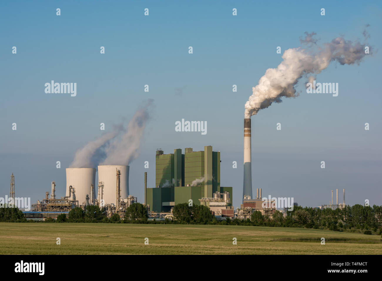 Large factory with steaming cooling towers and smoking chimney Stock Photo