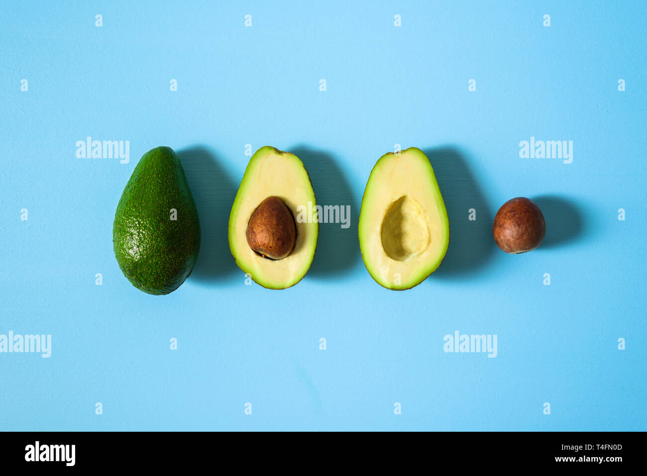 Avocado with half and seed on light blue background. Hard light Stock Photo