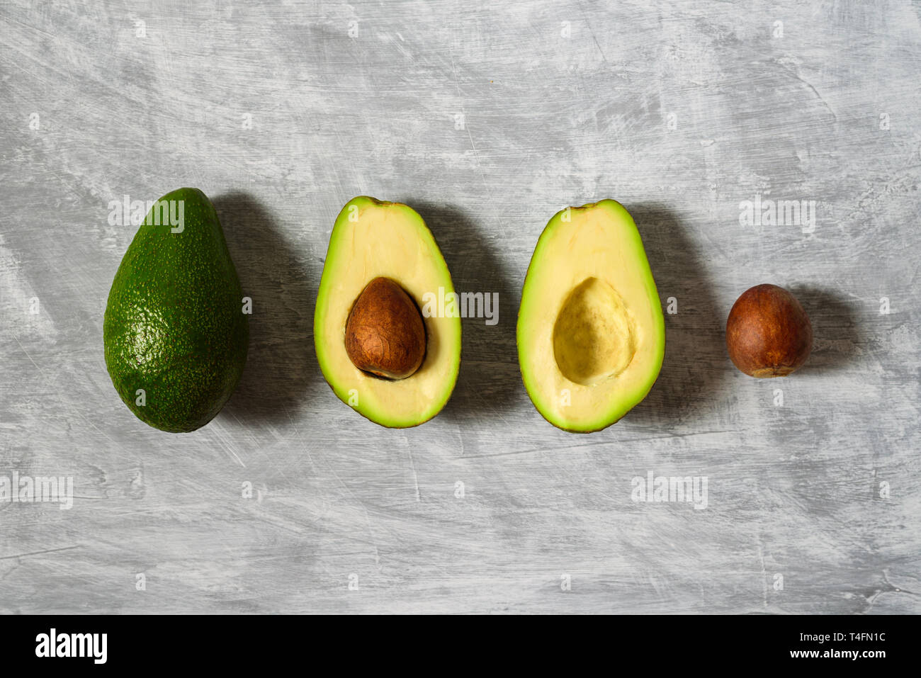 Avocado with half and seed on light grey background. Hard light Stock Photo