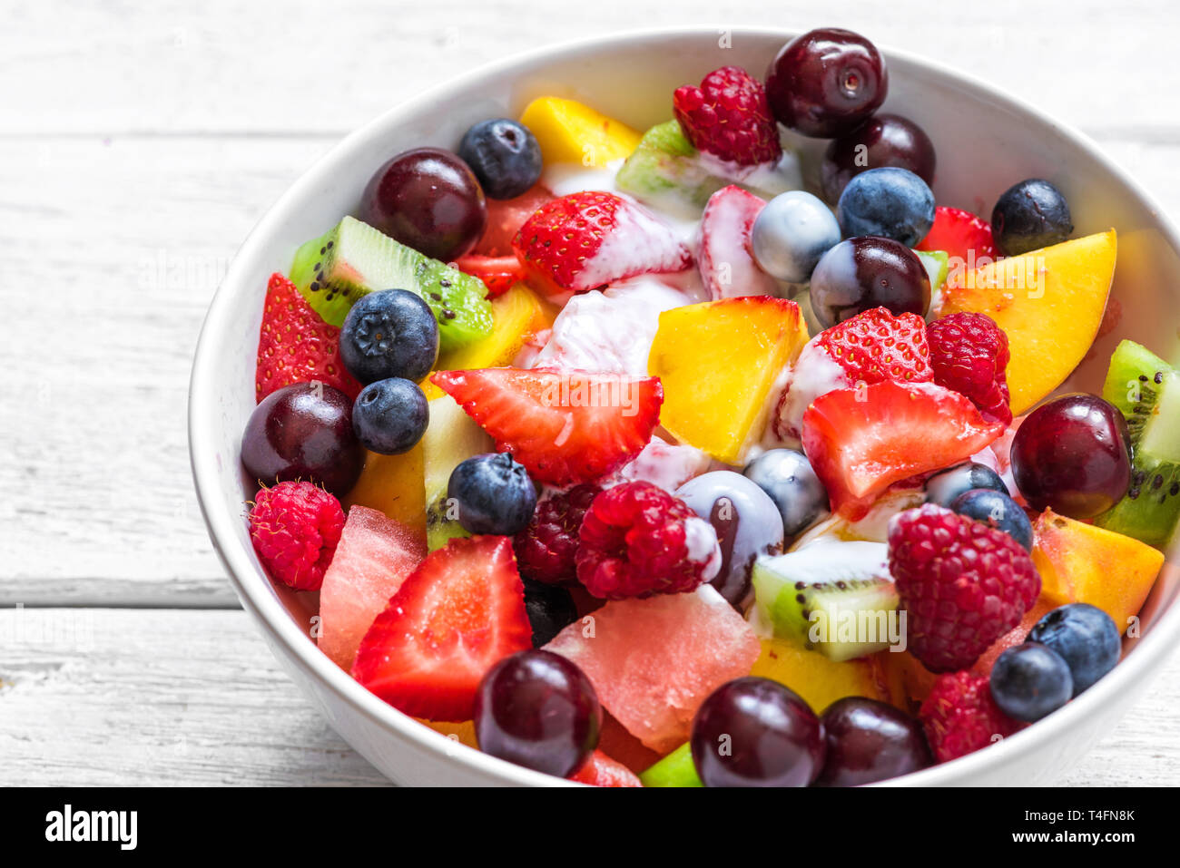 fruit salad with yogurt, watermelon, strawberry, cherry, blueberry, kiwi, raspberry and peaches in a bowl. healthy vegan food. close up Stock Photo