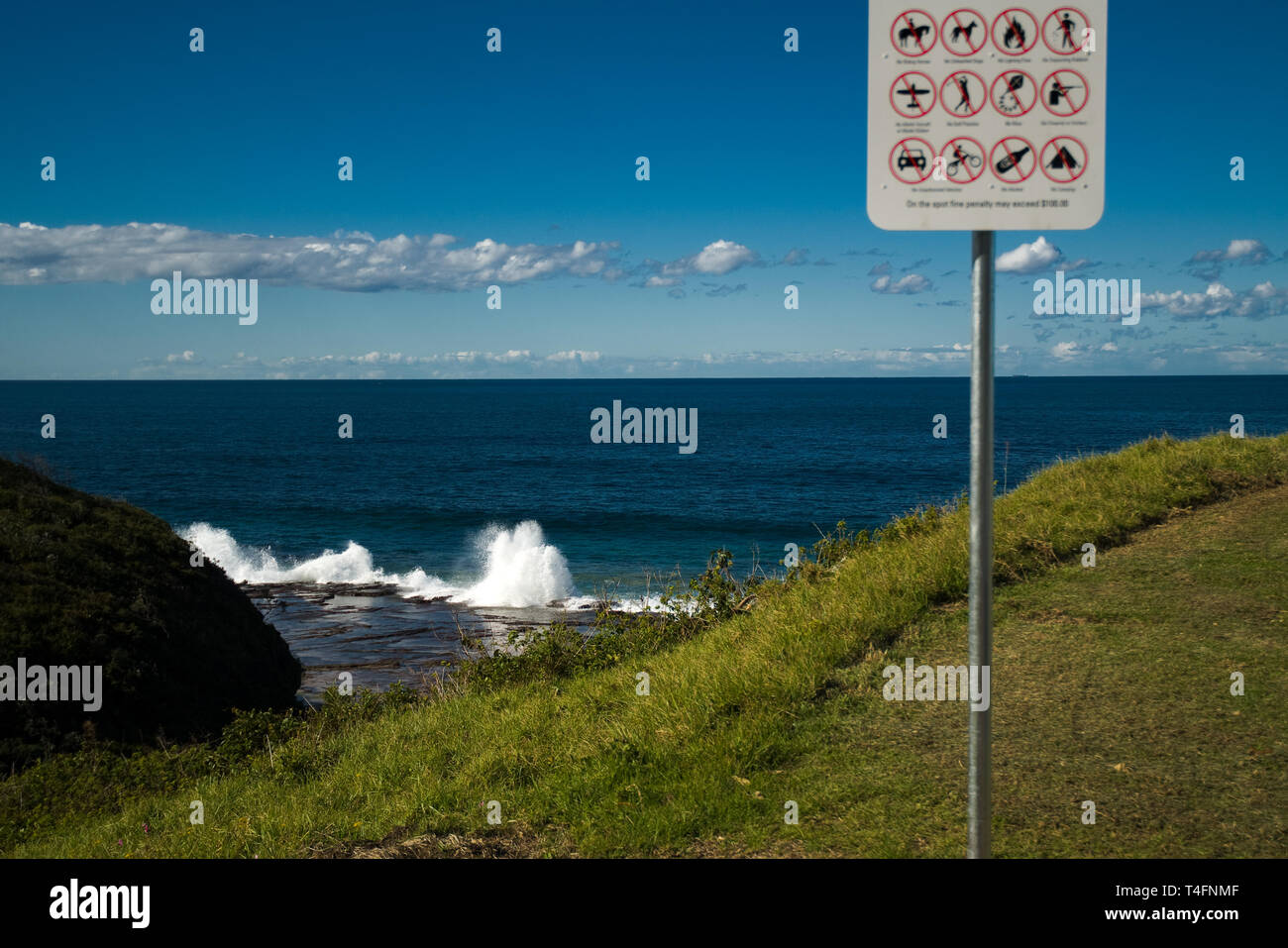 Warning Sign near Cliff with Ocean Surging against rocks Stock Photo ...
