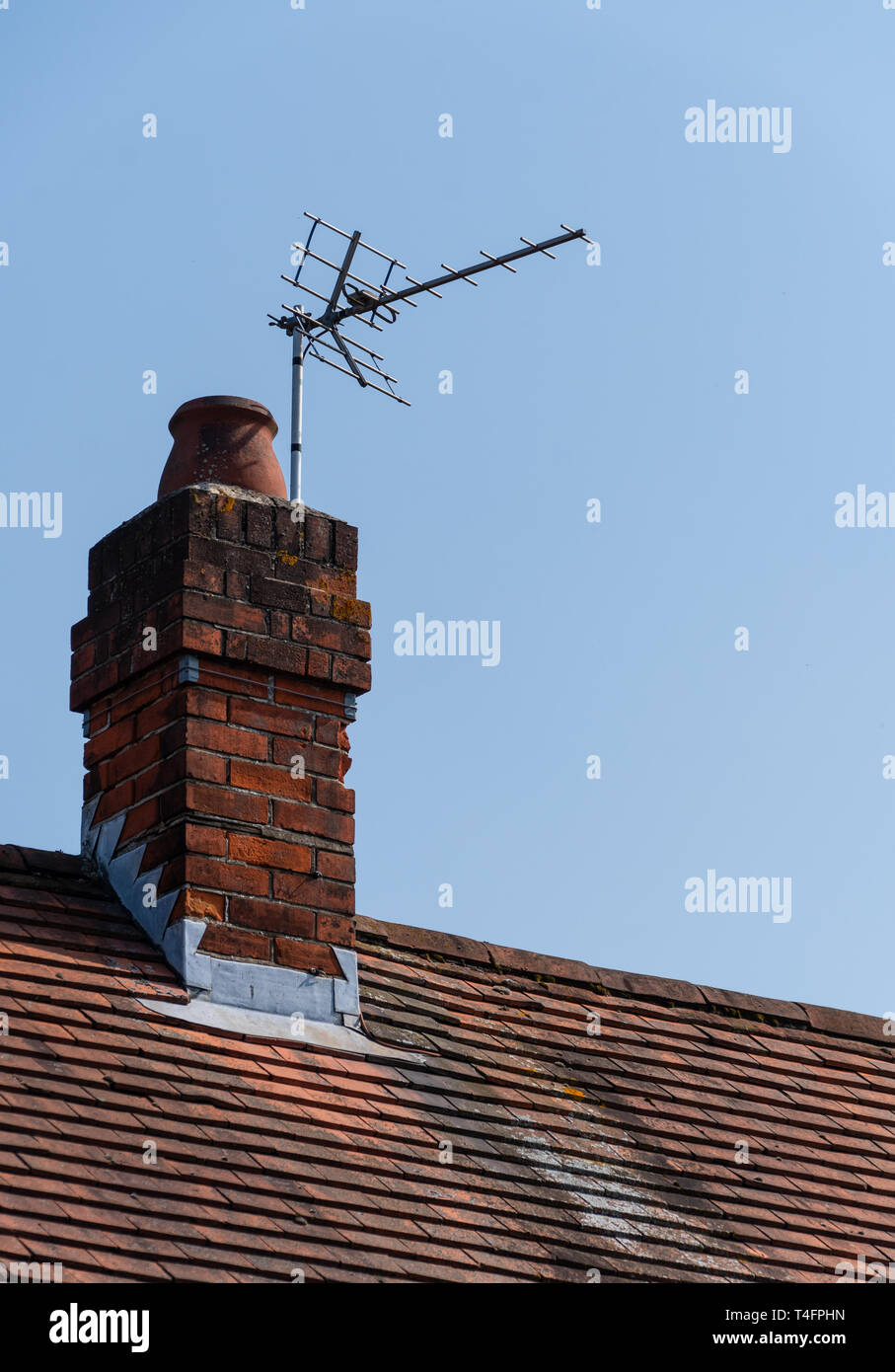 A analogue TV Aerial attached to a chimney on a roof top Stock Photo
