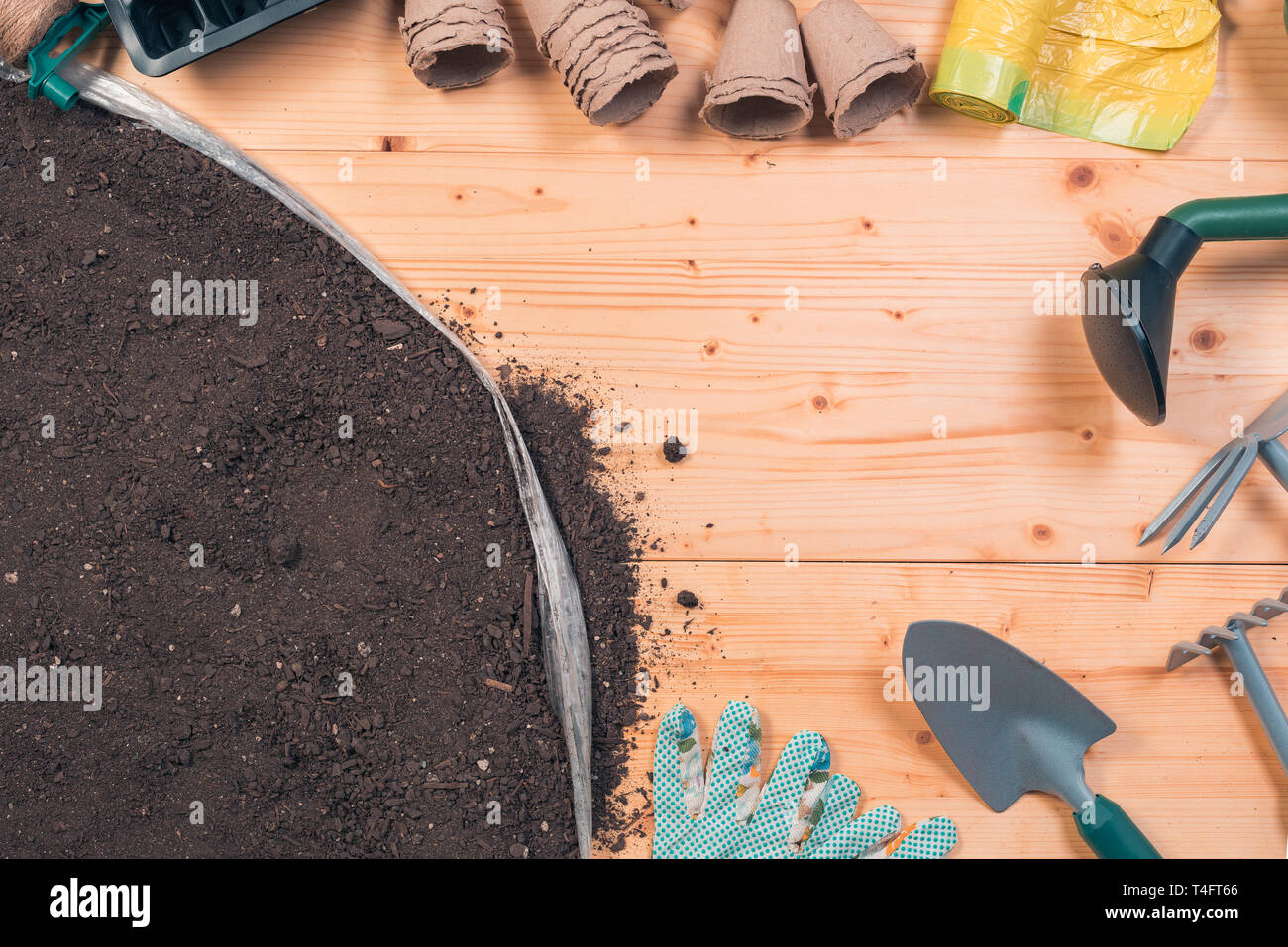 Gardening tools on potting soil, top view of equipment set on wooden background Stock Photo
