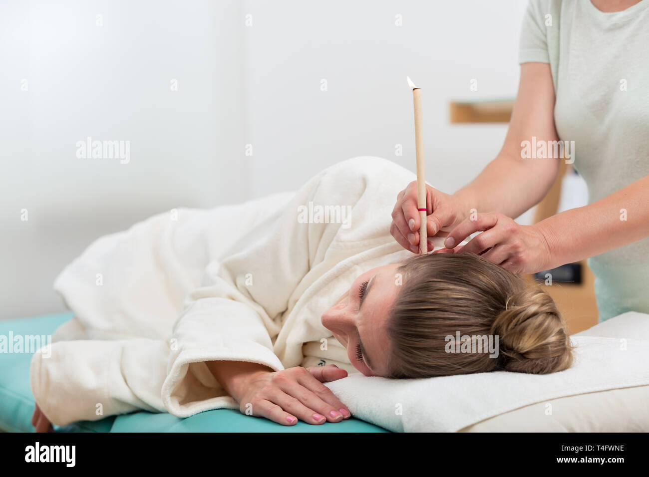 Therapist hand with burning ear candle in woman's ear Stock Photo Alamy