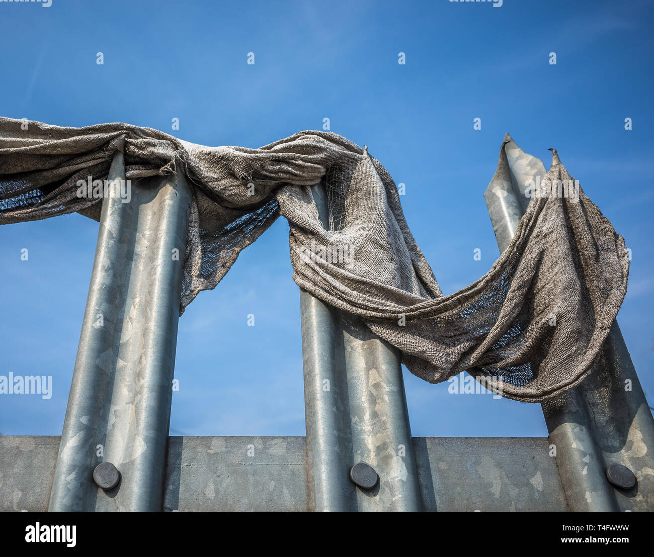 Old fabric cloth caught on metal spiked security barrier. Stock Photo