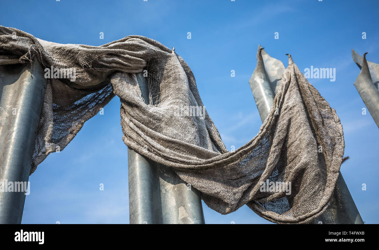 Old fabric cloth caught on metal spiked security barrier. Stock Photo