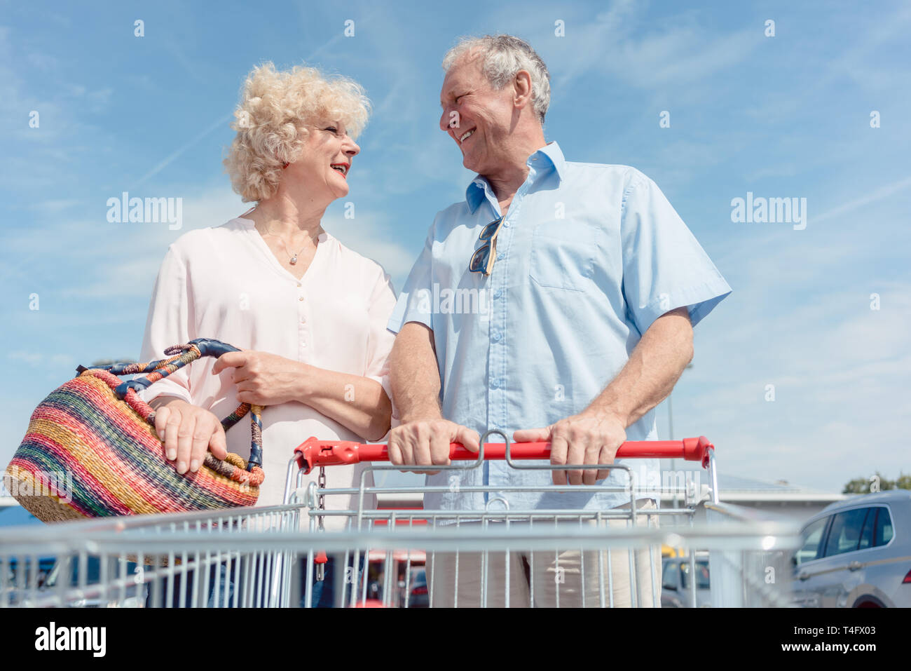 Senior man holding a shopping cart while looking at his wife with love Stock Photo