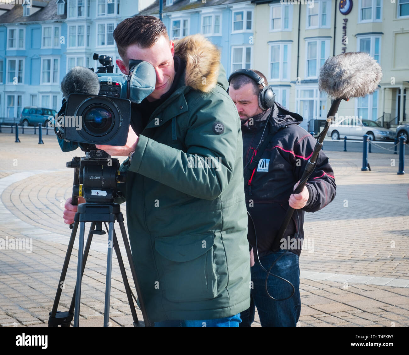 Media workers in the UK: A professional television crew  on location recording an item for broadcast, with the video camerman pointing his lens directly at the subject. UK Stock Photo