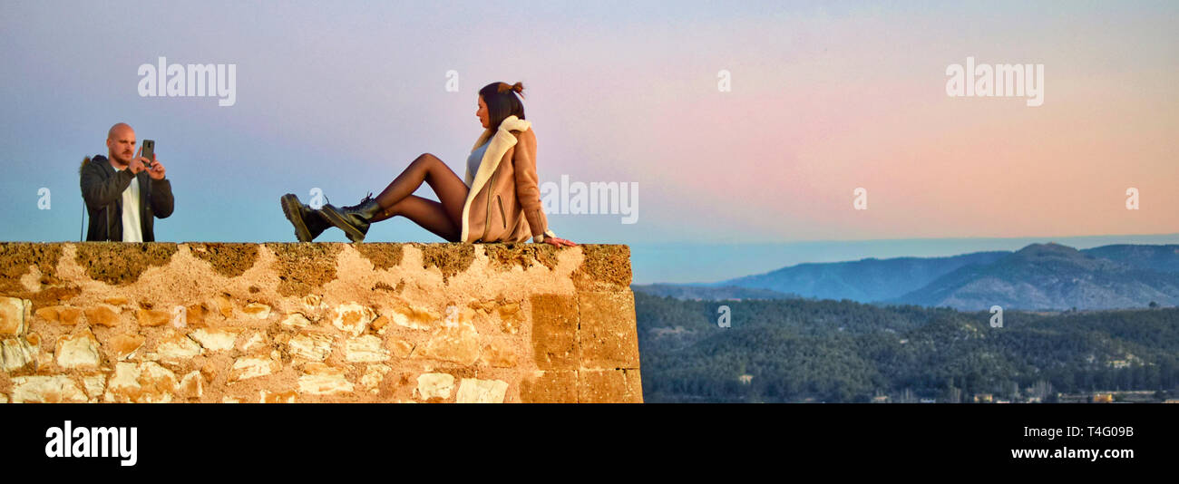 Caravaca, Spain, January 7, 2019: Tourist couple taking photo on the precipice of Caravaca castle in Spain. Dangerous pictures. Risky photos in cliffs. Stock Photo