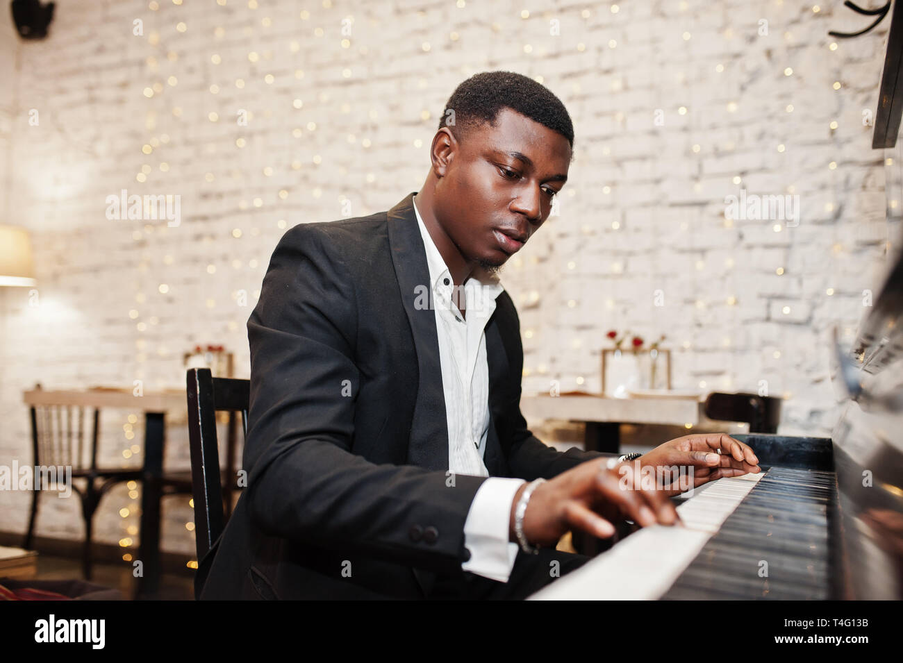 Strong powerful african american man in black suit play piano Stock