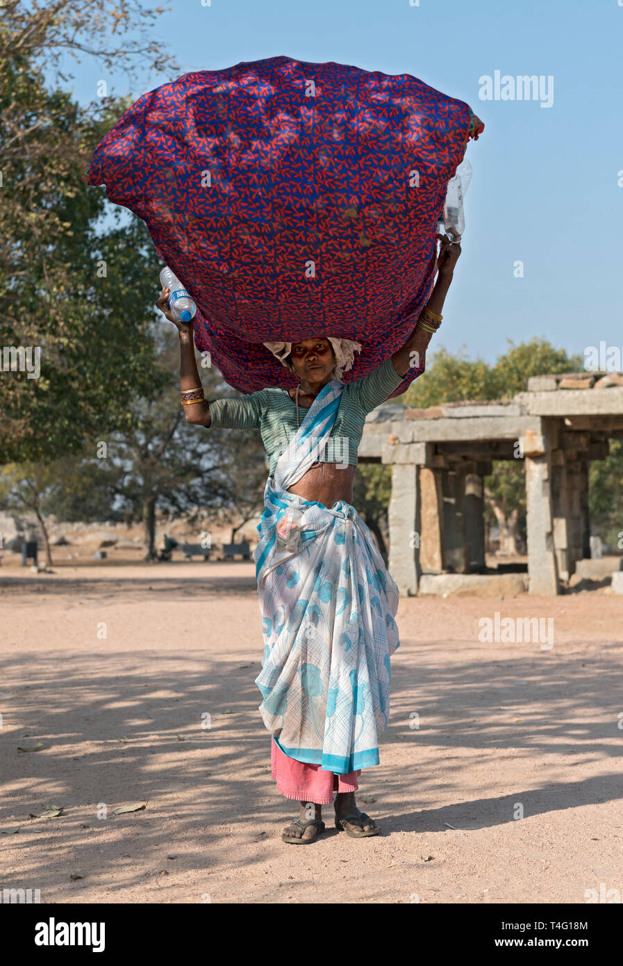 Woman carries heavy load on her head, Hampi, India Stock Photo