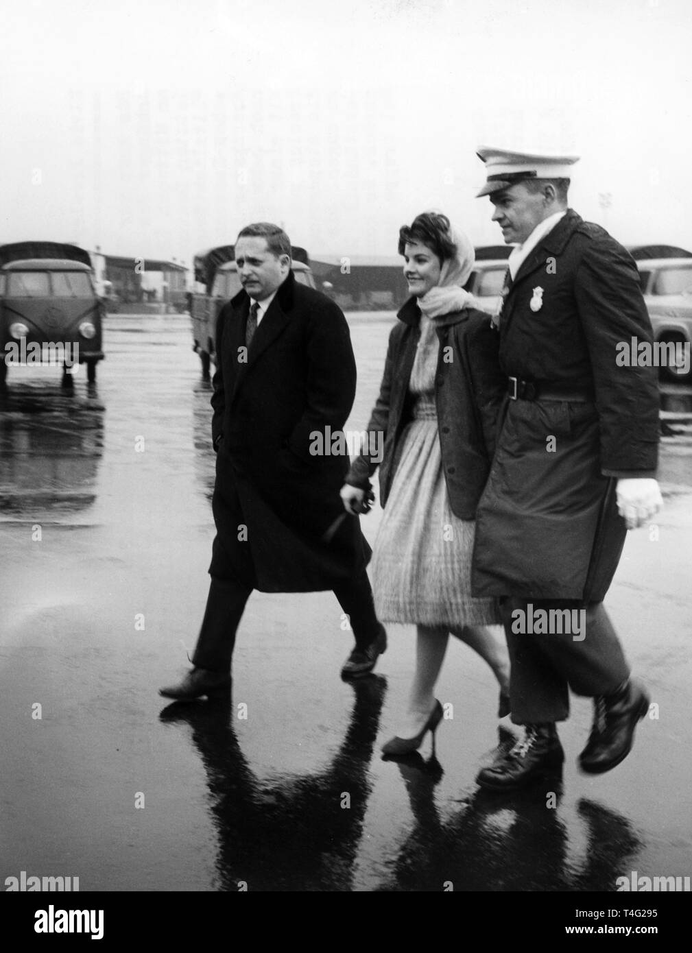 The 16-year-old Priscilla Beaulieu is accompanied by a policeman on the military airbase in Frankfurt on 02 March 1960. The girlfriend and later wife of the American Rock'n Roll singer Elvis Presley had crossed the cordon of police to take leave of Elvis before his flight back to the States. Presley was deployed as a soldier in Hesse and got to know the stepdaughter of a Canadian air force officer in Bad Nauheim in 1959. They married in Las Vegas in 1967. | usage worldwide Stock Photo