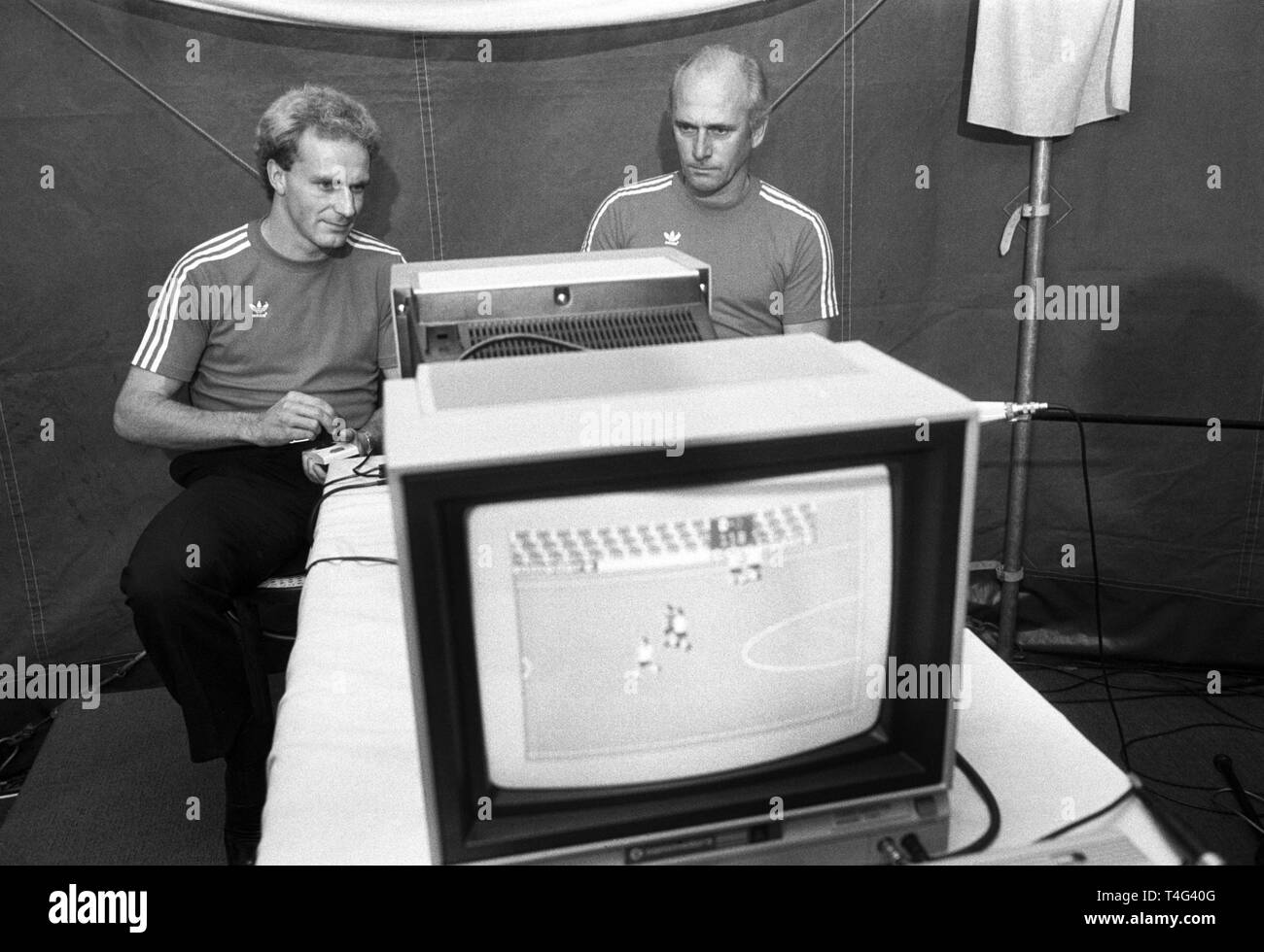Der Münchner Bayern-Trainer Udo Lattek (r) und sein Stürmer Karl-Heinz Rummenigge sitzen am 20.10.1983 auf der 'System 83'-Ausstellung in München an einem Fußball-Computerspiel. | usage worldwide Stock Photo