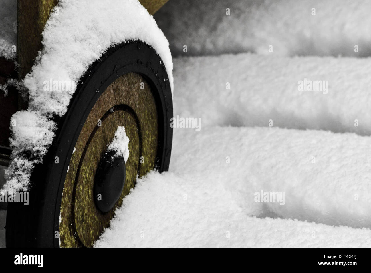 close up of snow settling on a wooden wheel of a cart Stock Photo
