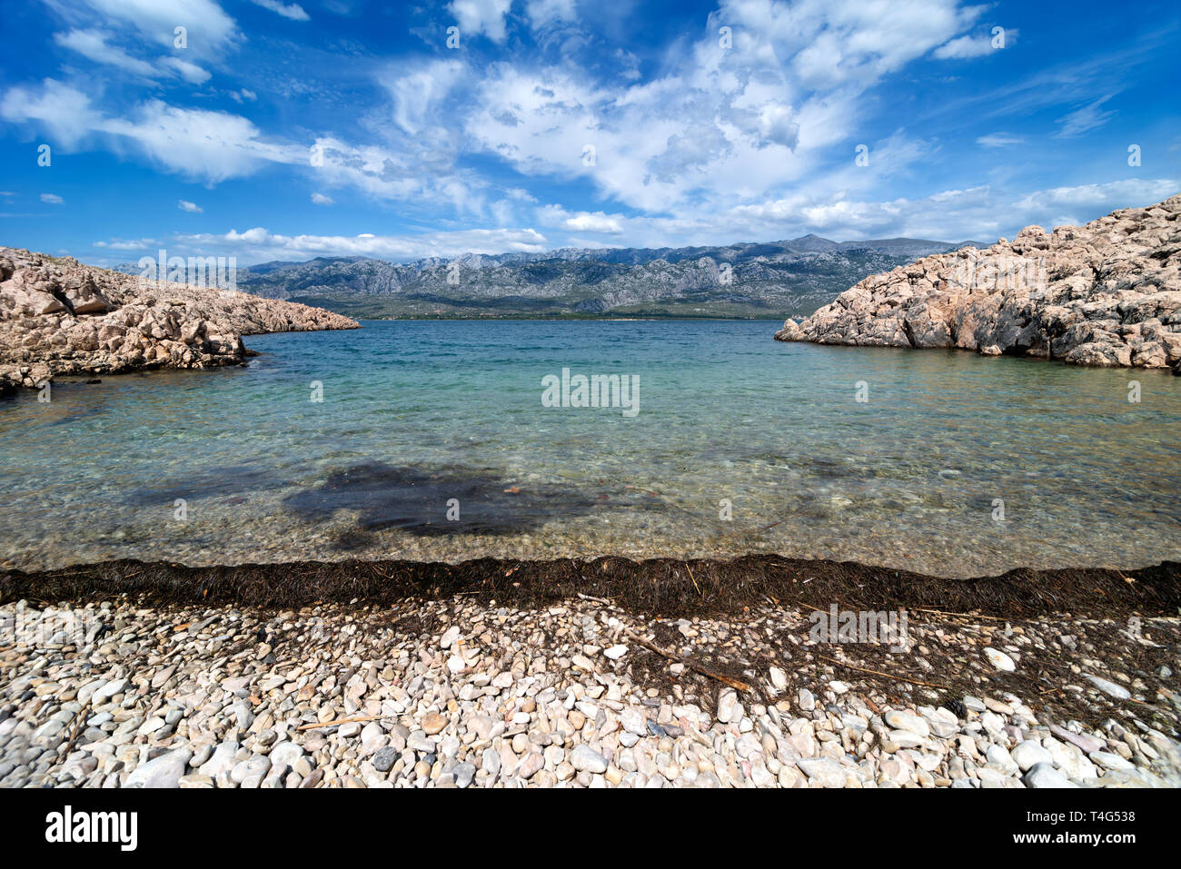 Quiet bay with Paklenica National Park Mountains in background. Beautiful ocean and dramatic blue sky with clouds on hot summer day. Stock Photo