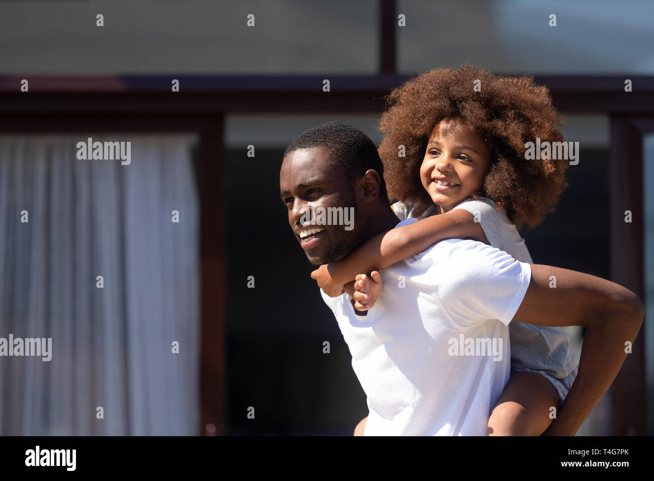 African American man holding daughter on back, playing outdoor Stock Photo