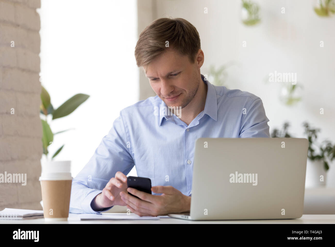 Smiling businessman using smartphone in his workplace Stock Photo