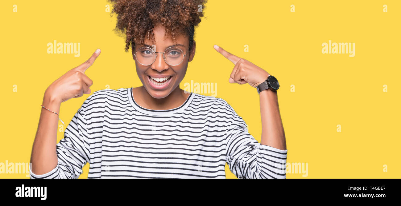 Beautiful young african american woman wearing glasses over isolated background Smiling pointing to head with both hands finger, great idea or thought Stock Photo