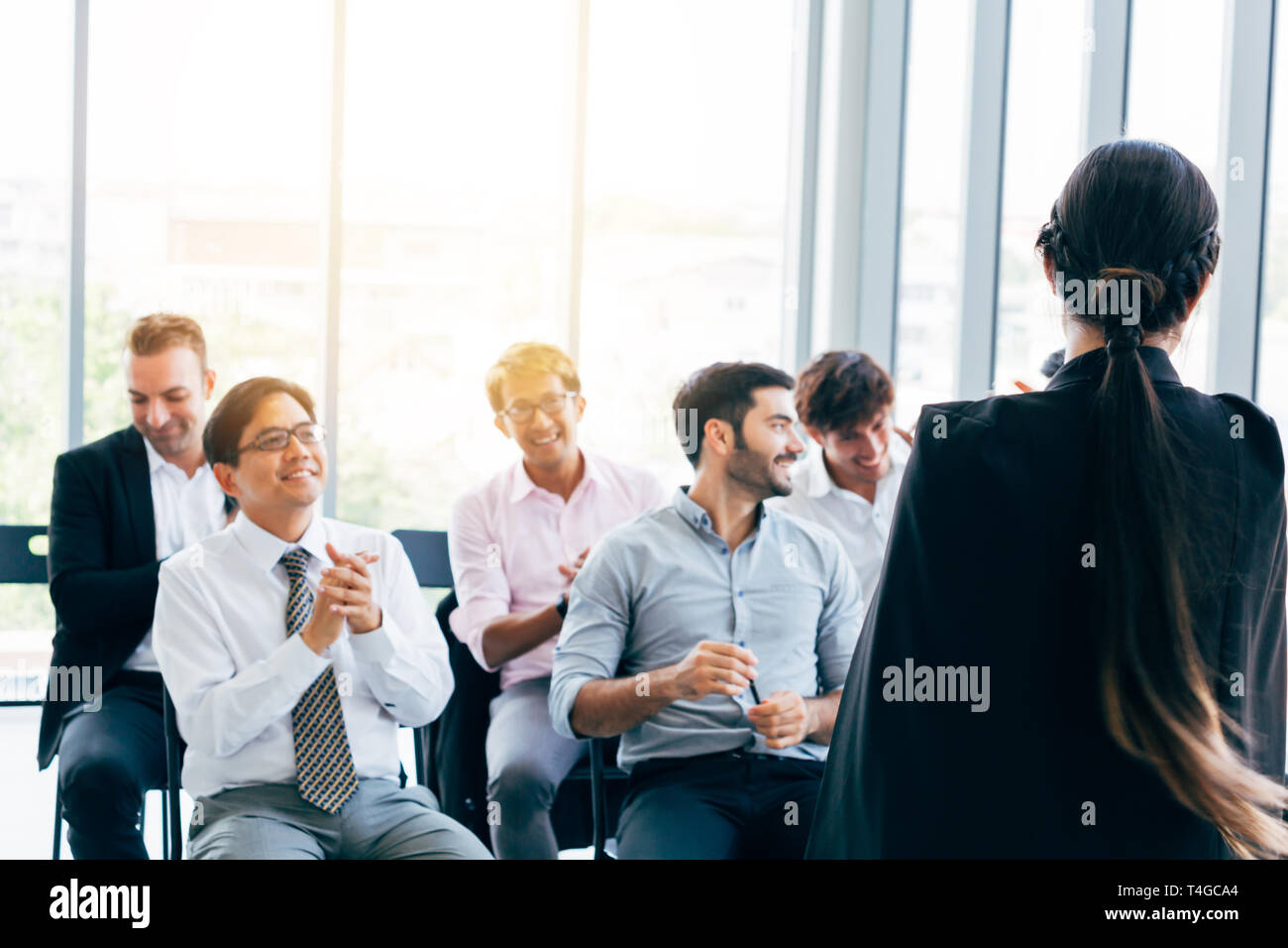 Back view of stylish woman giving presentation for male colleagues working together in office Stock Photo