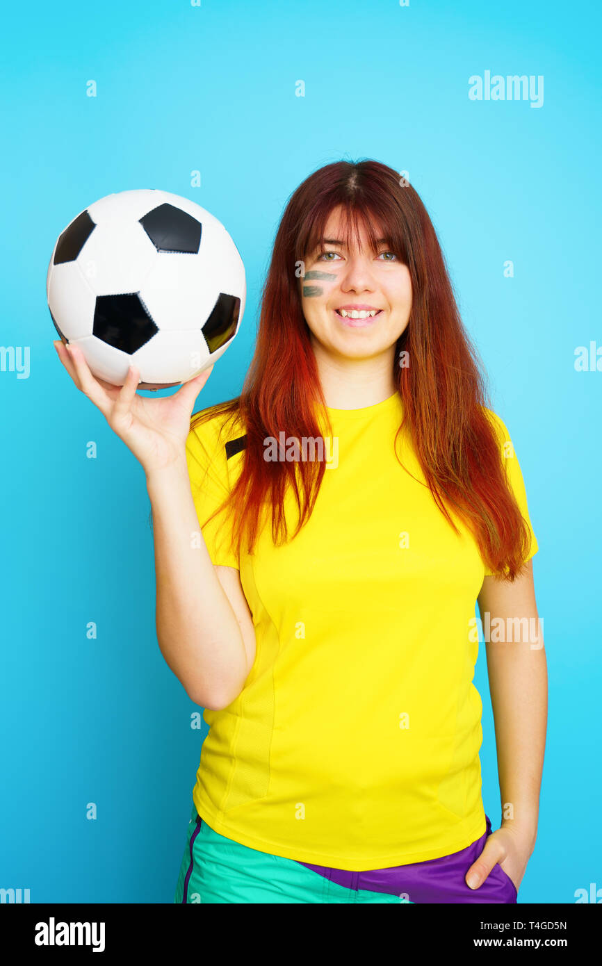 Woman is socccer fan in yellow t-shirt with soccer ball Stock Photo