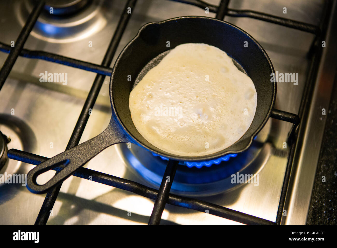 Photo from above of frying pan with pancake on gas stove Stock Photo