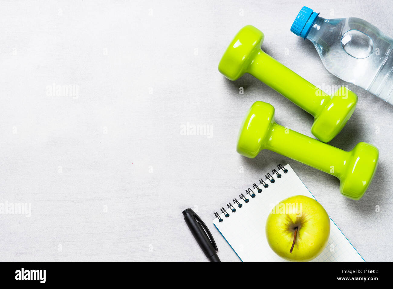 Dumbbells, measuring tape, water and apple top view. Stock Photo