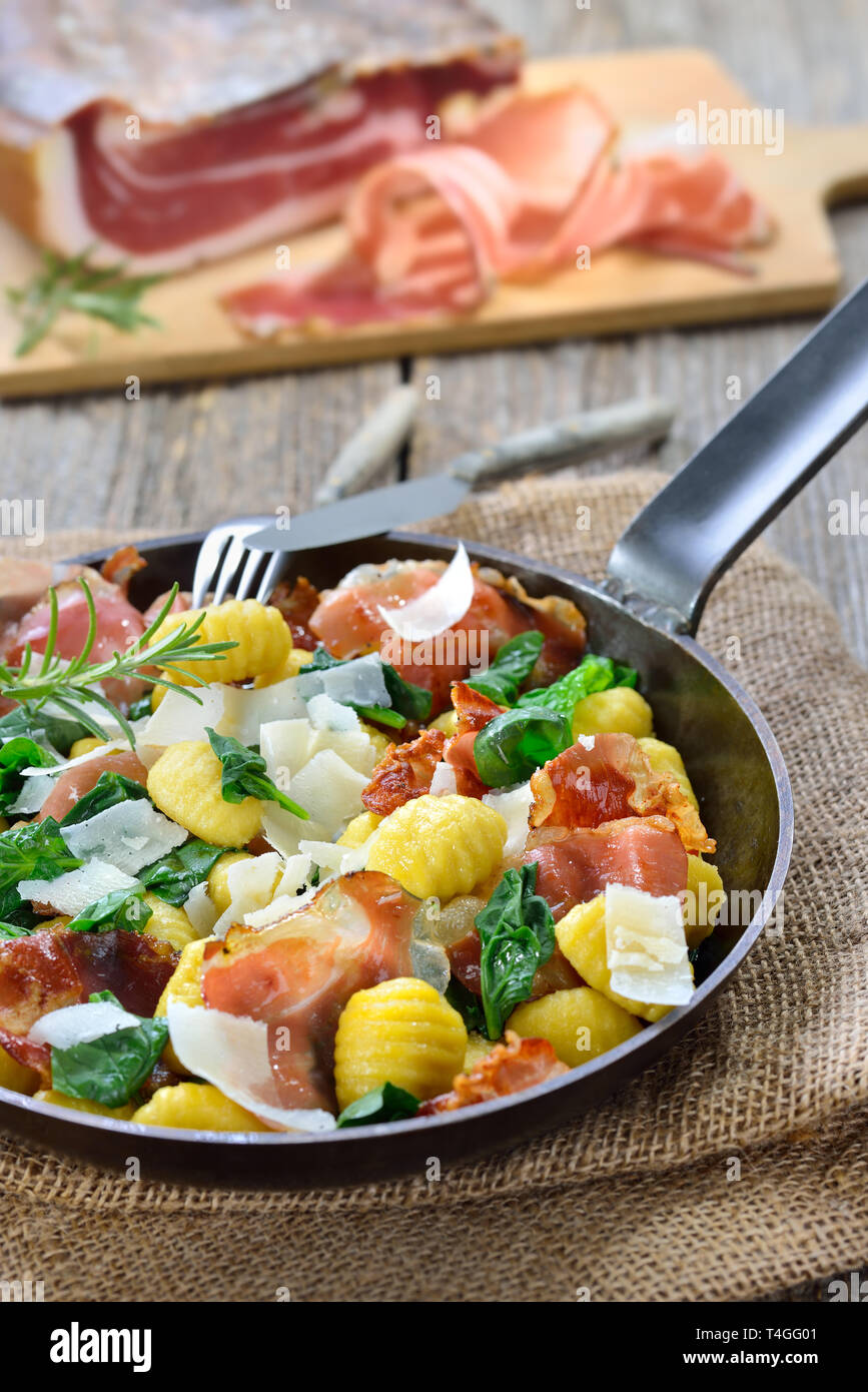Fried Italian gnocchi with fresh spinach leaves, crispy roasted South