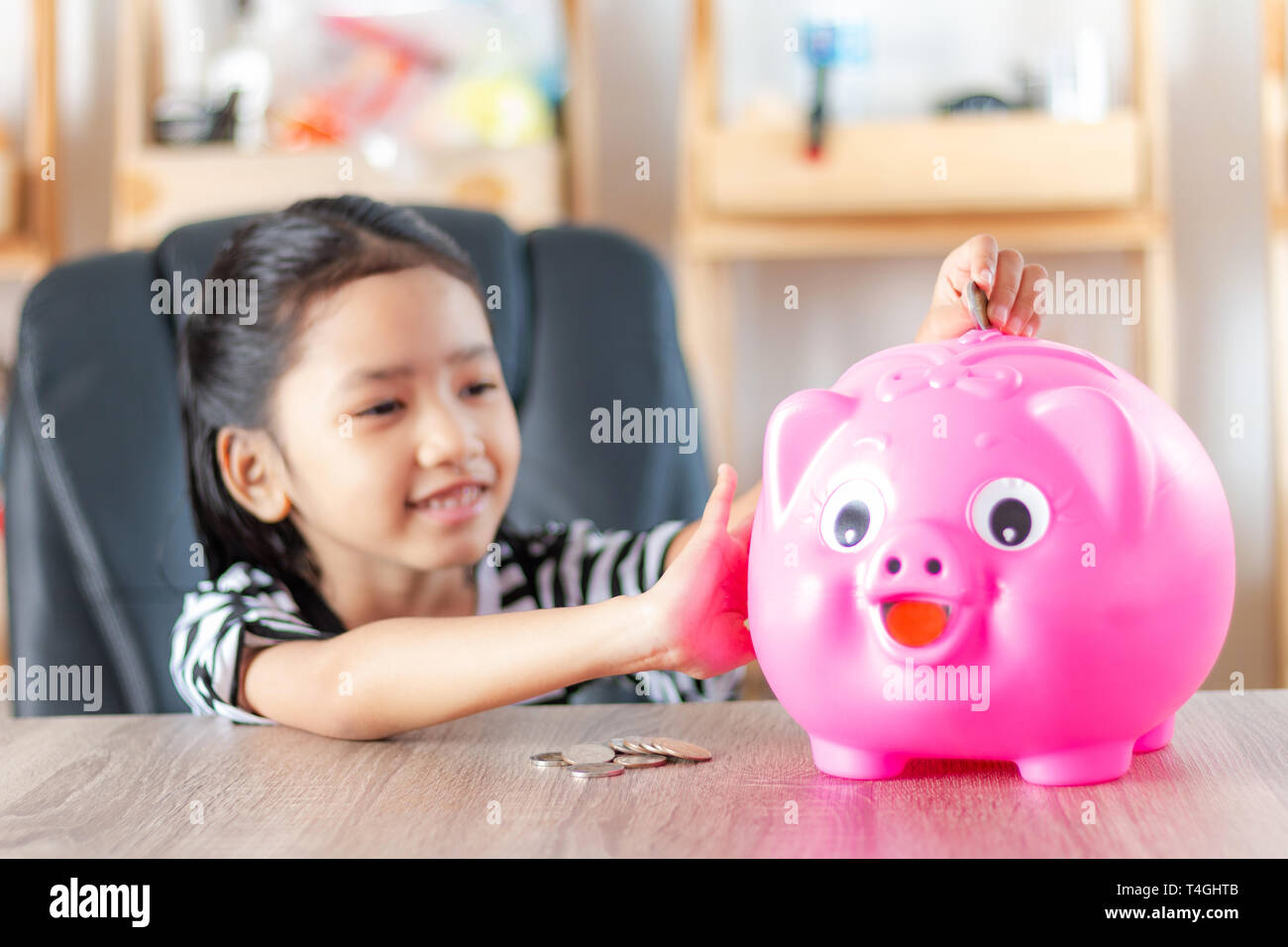 Asian little girl in putting coin in to piggy bank shallow depth of ...