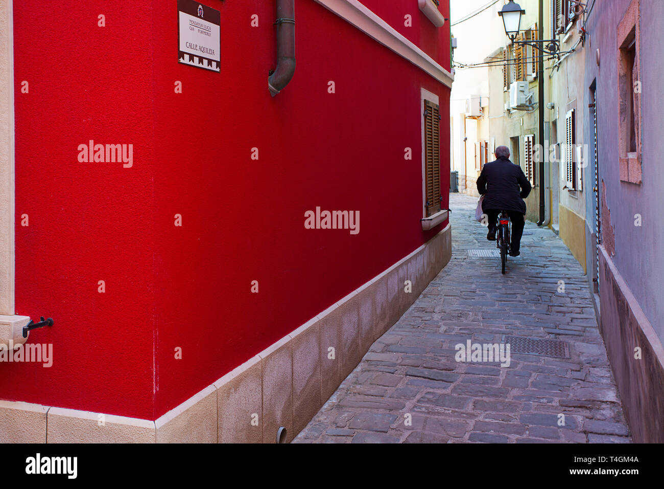 Old man cycling along a narrow street Stock Photo Alamy