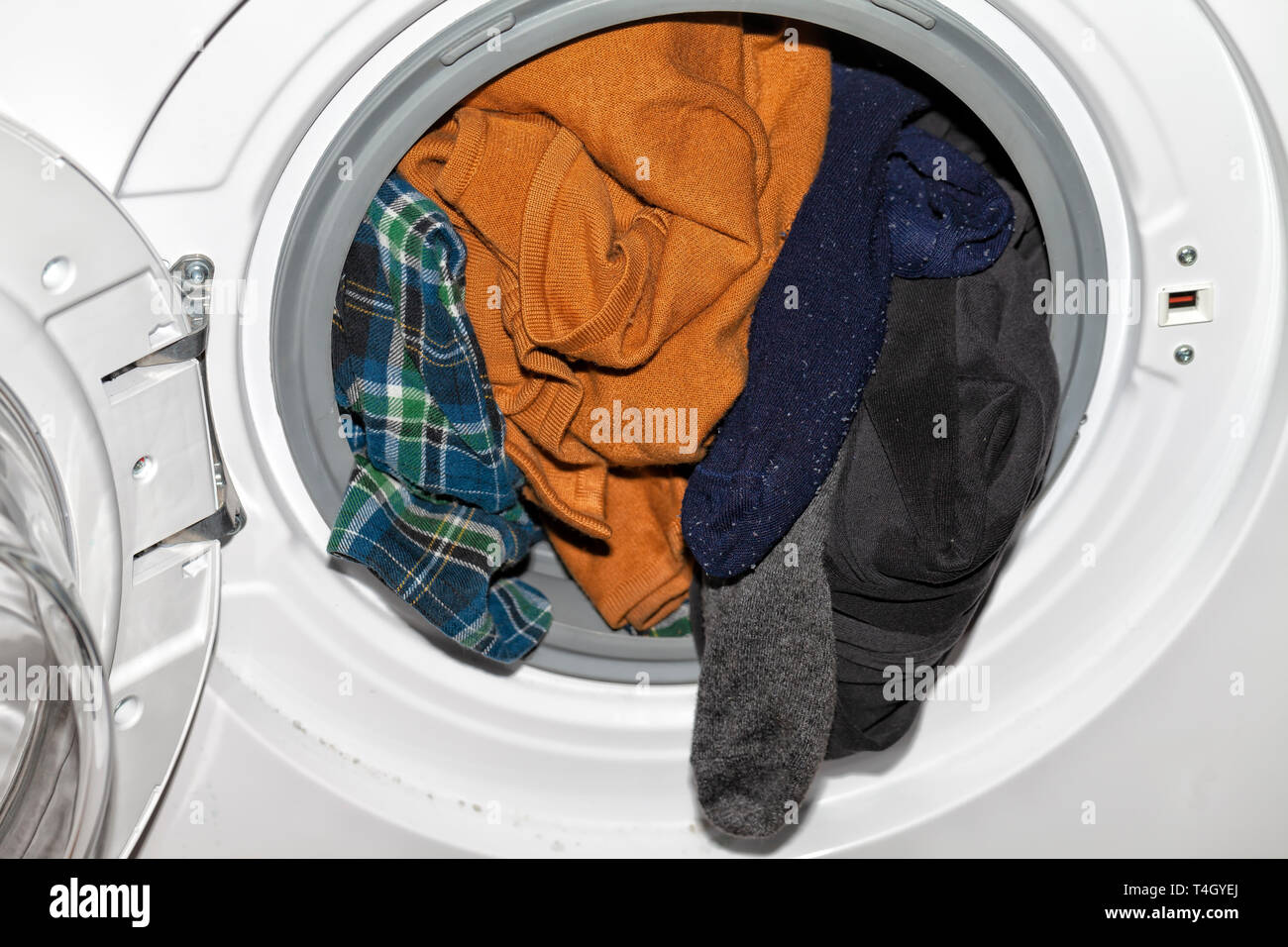 An automatic clothes washer with a lot of dirty clothes inside Stock