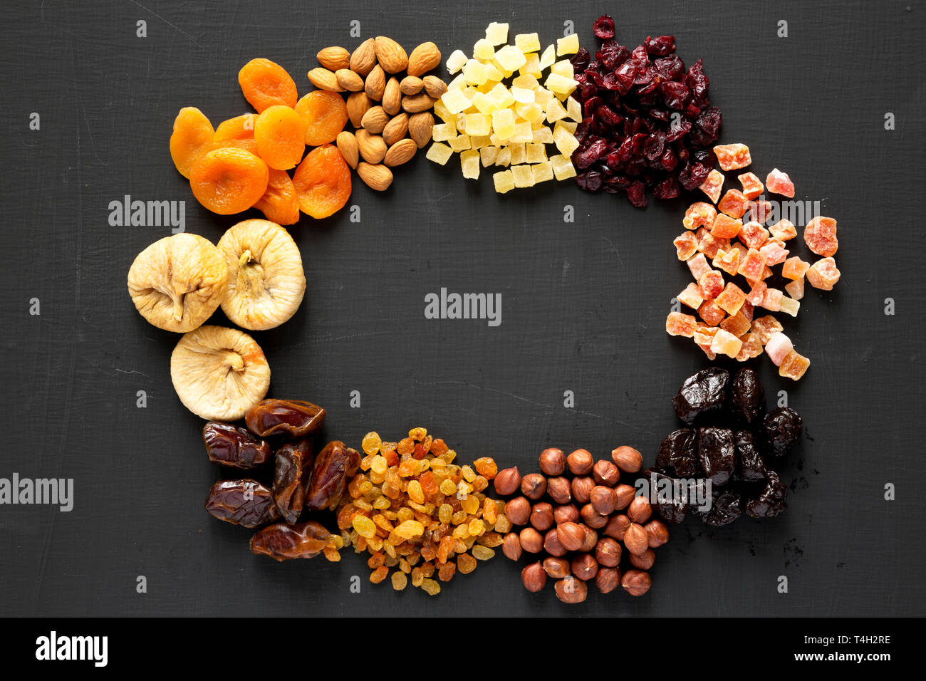 Frame of dried fruits and nuts on a black background, top view
