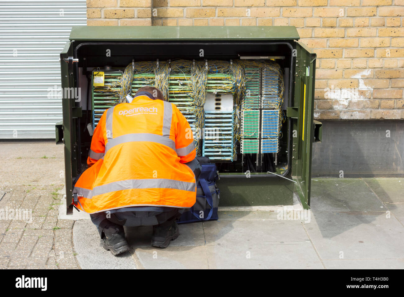 A BT Openreach engineer in front of a telephone cabinet on a street in the UK Stock Photo