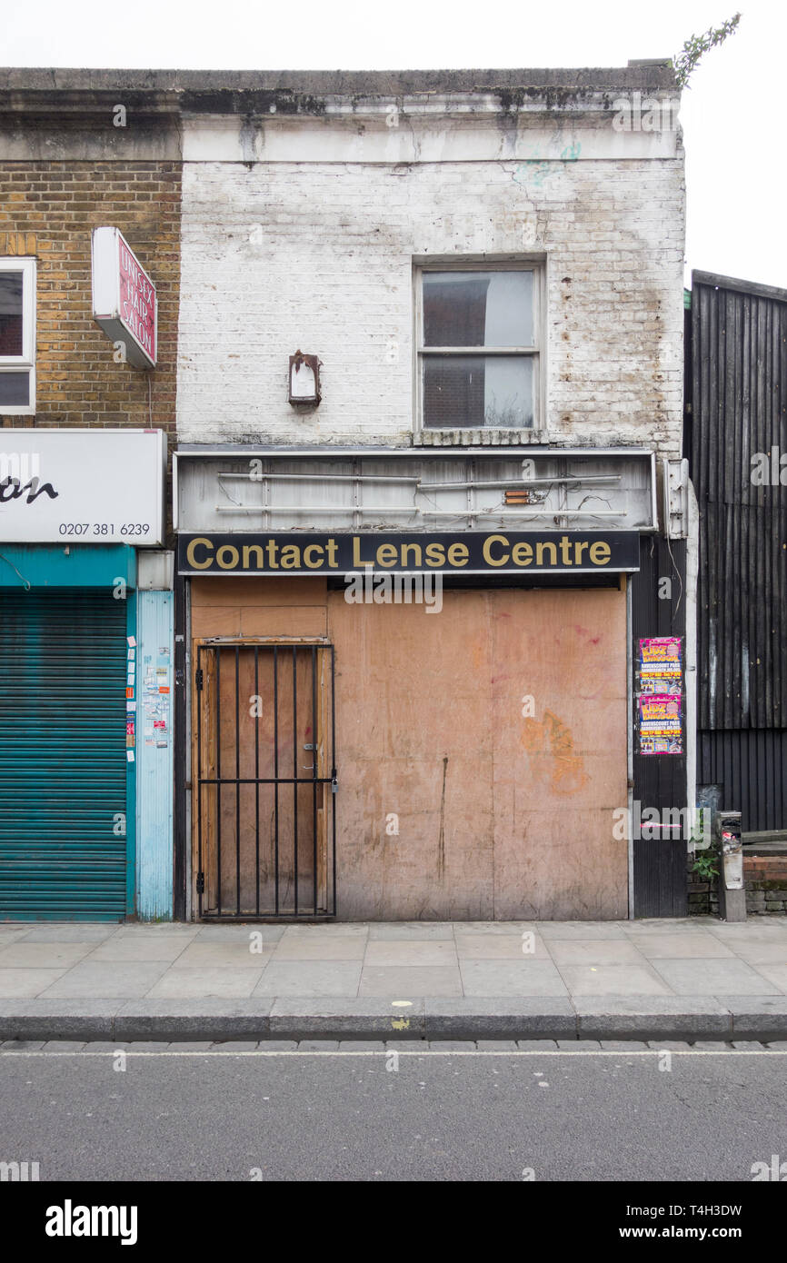 A boarded-up contact lens shop front in Fulham, London, UK Stock Photo