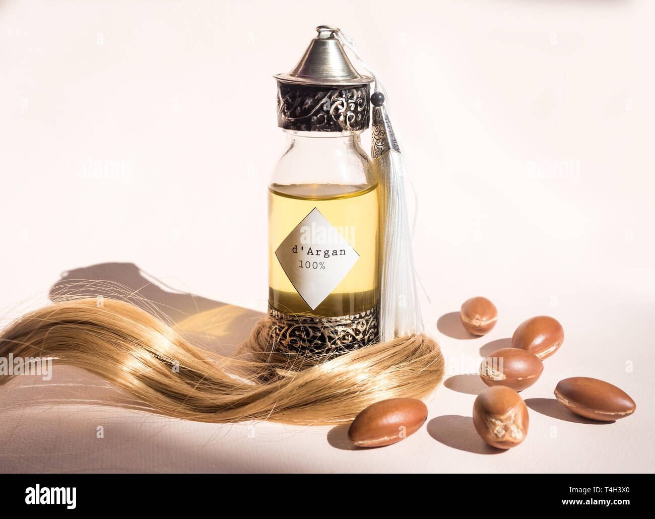 Curll hair of golden hair and decorative bottle with iron embossed in  traditional Moroccan style with precious Moroccan argan oil and nuts ander  Stock Photo - Alamy